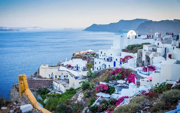 The white cliffside houses and blue-domed rooftops of Oia in Santorini, Greece, above the caldera