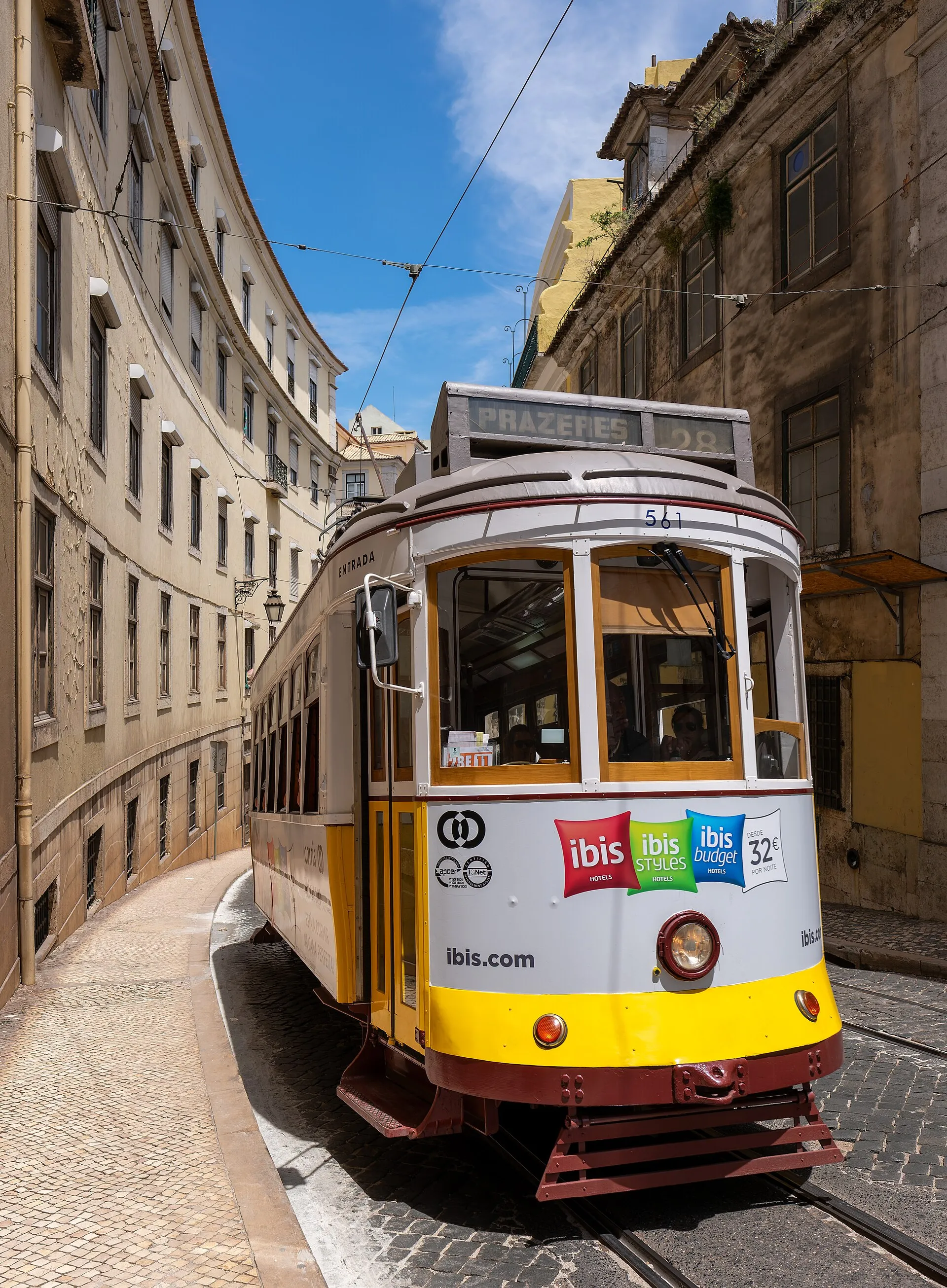 A yellow Tram 28 climbing a steep street in Lisbon