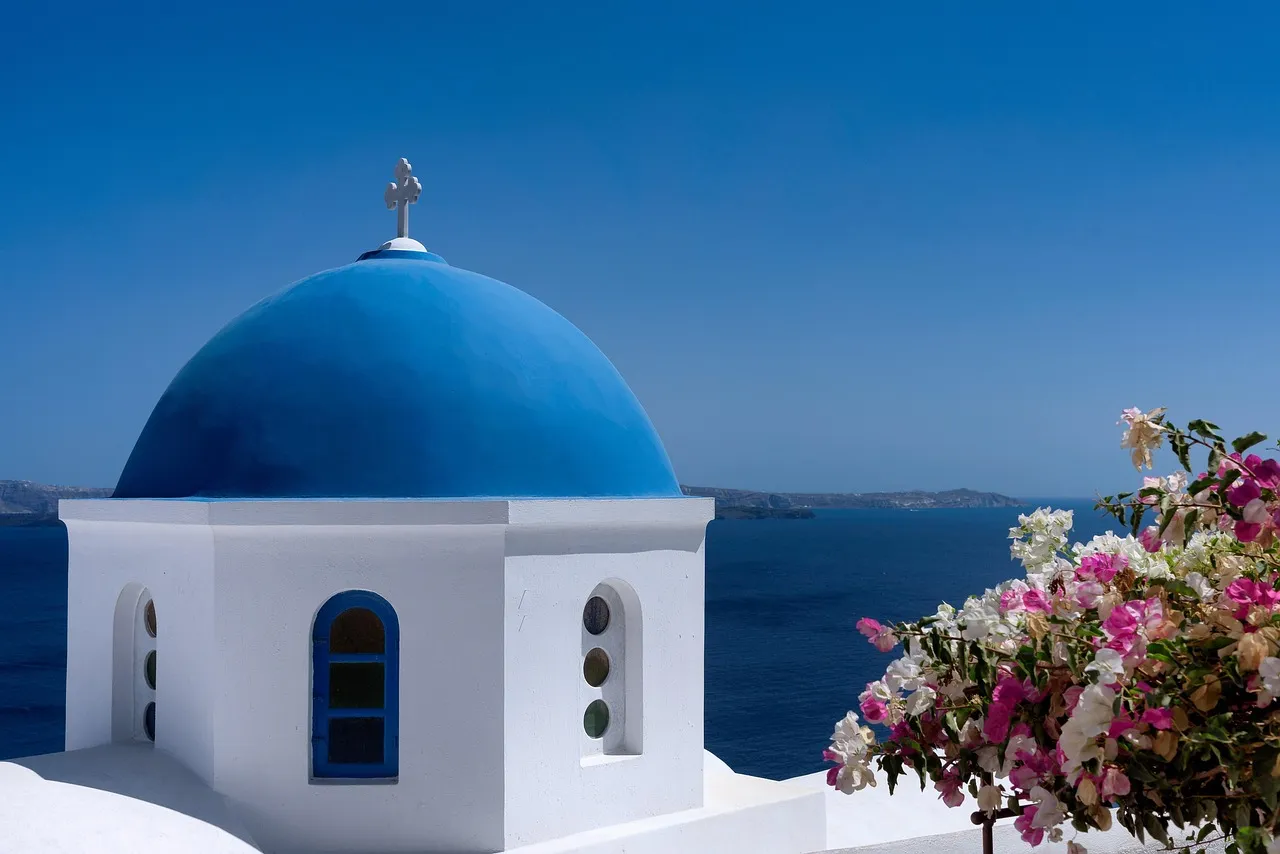 White-washed houses and a blue dome on a Santorini hillside