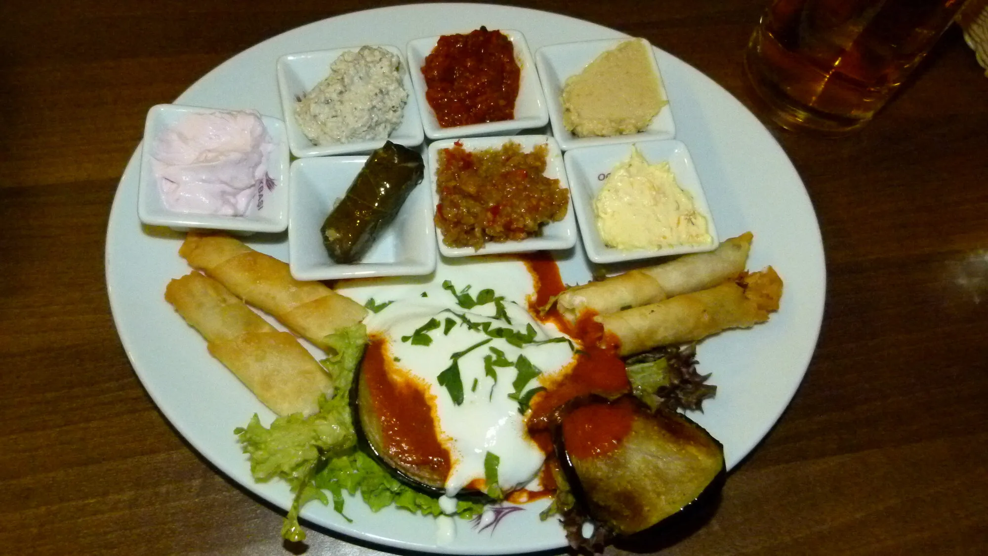 A mixed Turkish meze platter with small bowls of dips and stuffed vine leaves
